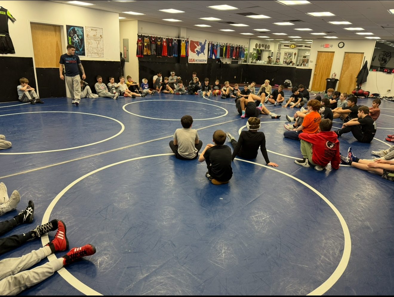 Ruthless Wrestling Club elite training class gathered on the mat with a coach