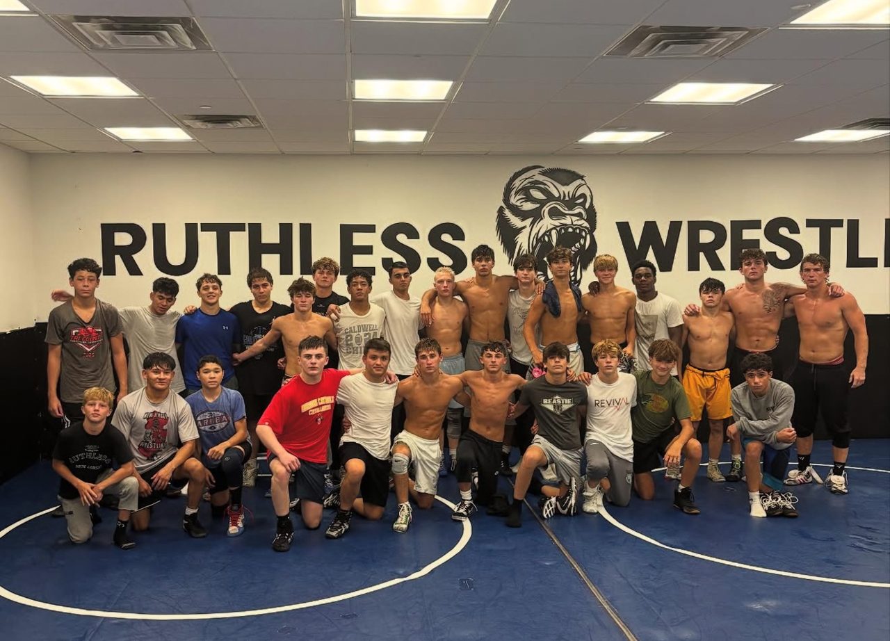 Ruthless Wrestling Club high school wrestling team gathered in the training room under the wall logo